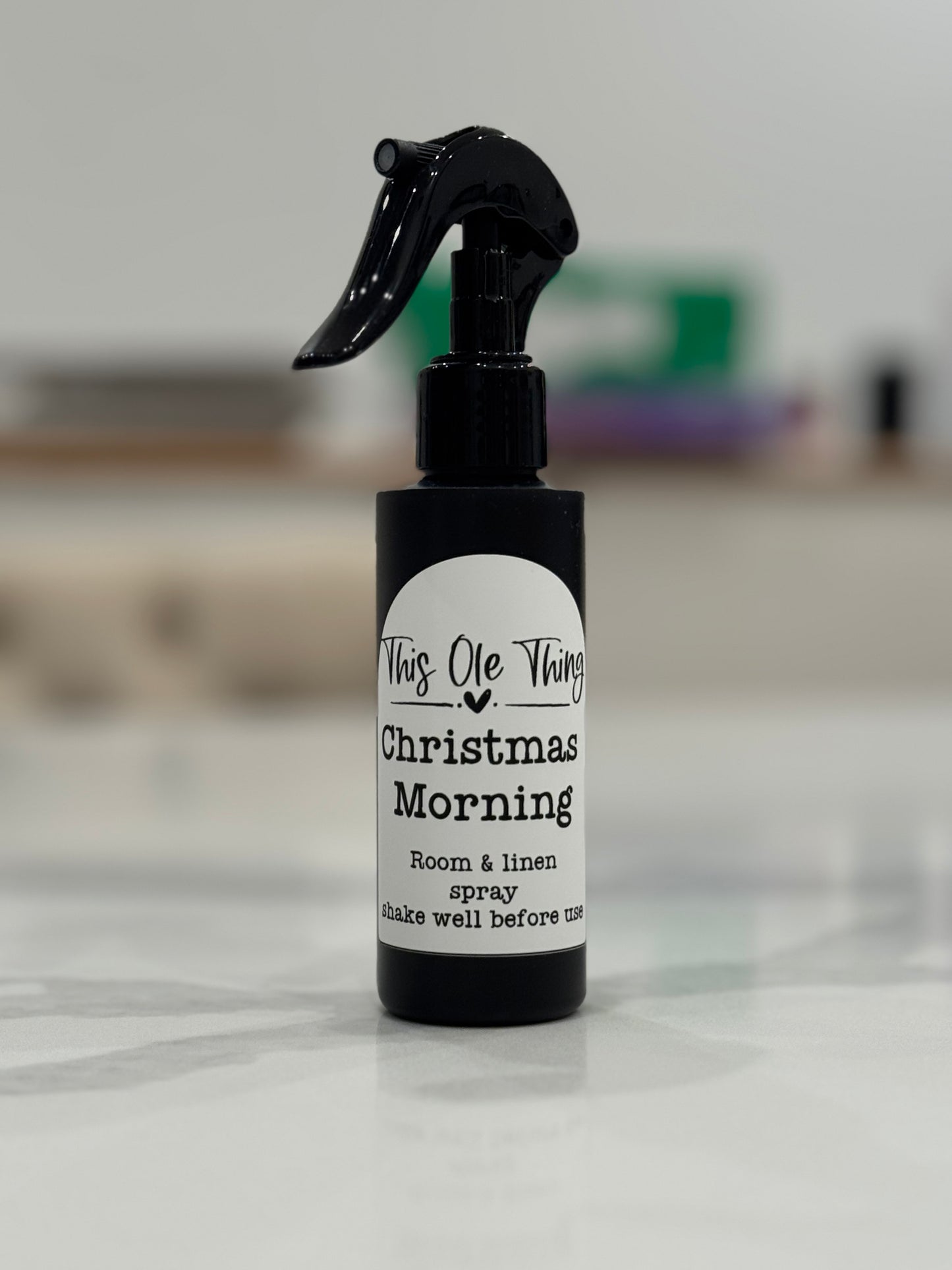Room spray bottle labeled 'Christmas Morning' on a light surface with a blurred background