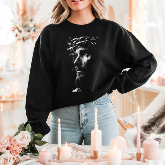 Person wearing a black sweatshirt with a graphic design, standing in a decorated room with candles and flowers.