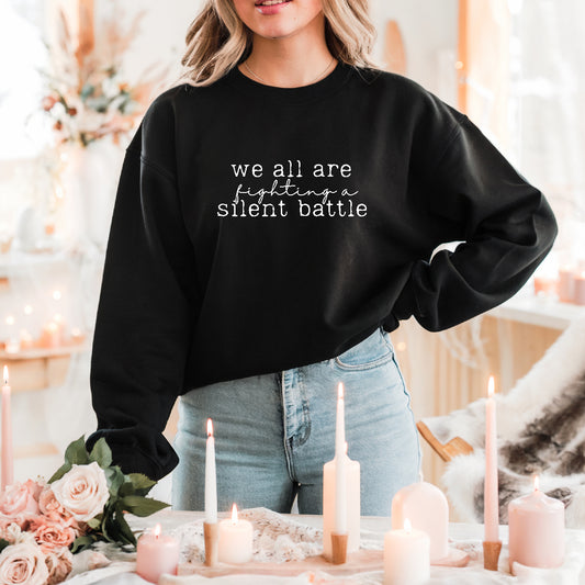 Person wearing a black sweatshirt with text in a cozy indoor setting with candles and flowers.