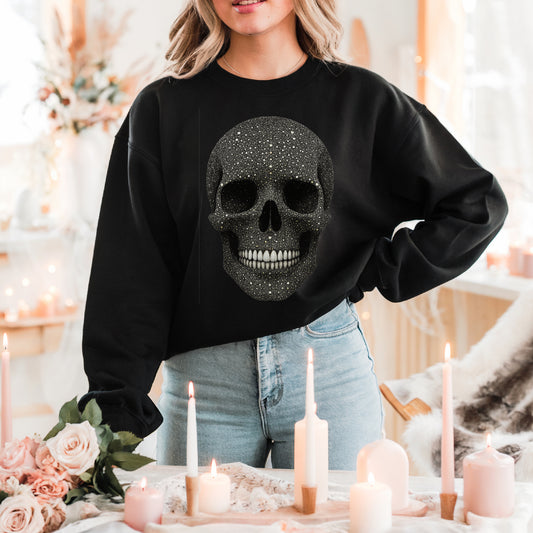 Person wearing a black sweatshirt with a skull design in a cozy indoor setting with candles and flowers.