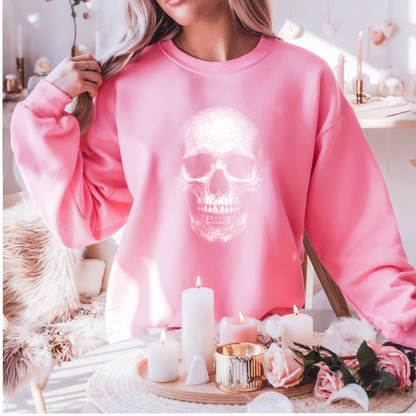 Person wearing a pink sweatshirt with a skull design, standing in a decorated room with candles and flowers.